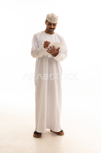 رجل عماني بالزي التقليدي يكتب أمام خلفية بيضاء