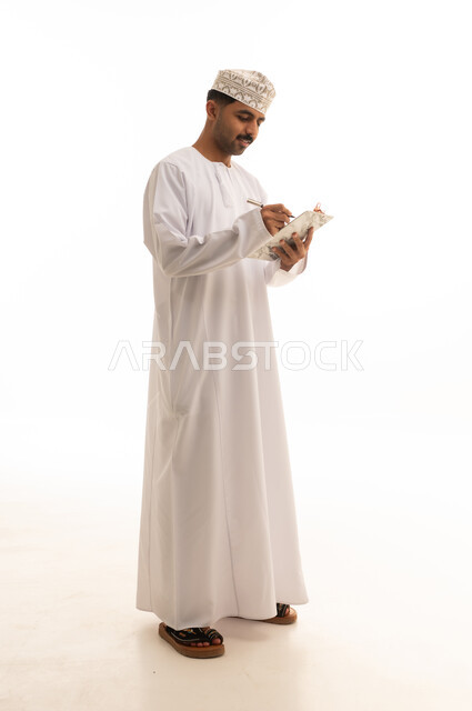رجل عماني بالزي التقليدي يكتب على خلفية بيضاء