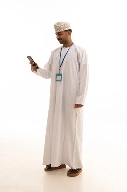 رجل عماني بالزي التقليدي يستخدم الهاتف الذكي