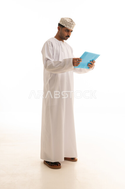 Omani Man in Traditional Dress Reading Blue Folder