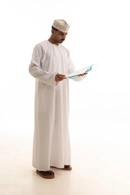 رجل عماني بالزي التقليدي يقرأ كتاباً في الاستوديو