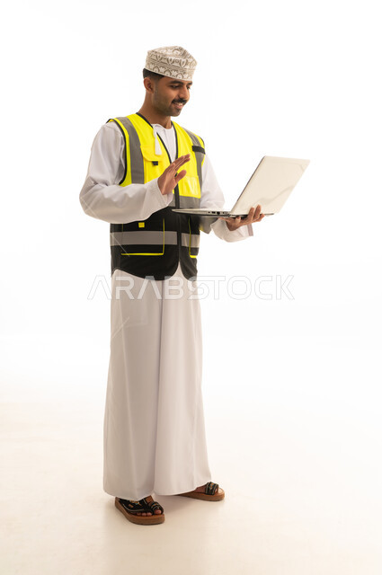 مهندس عماني بسترة السلامة يستخدم الحاسوب المحمول