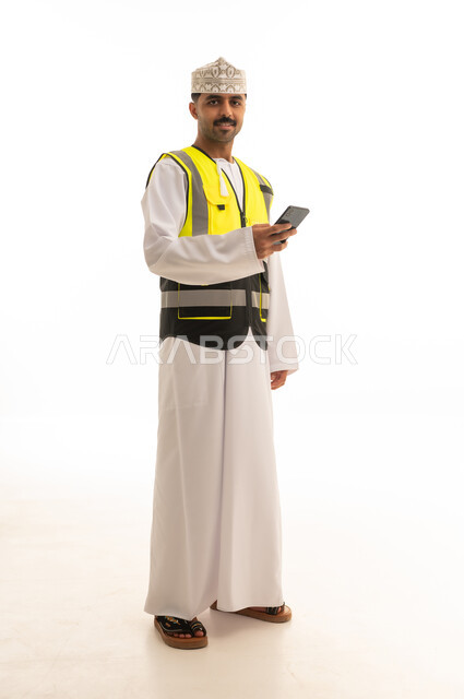مهندس عماني يرتدي سترة السلامة ويستخدم الجوال