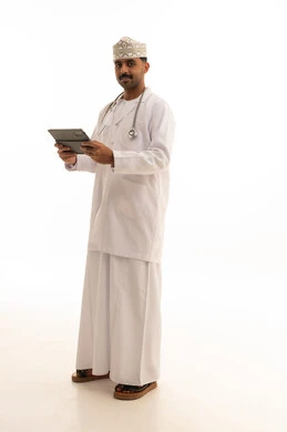 طبيب عماني يمسك جهاز لوحي بخلفية بيضاء