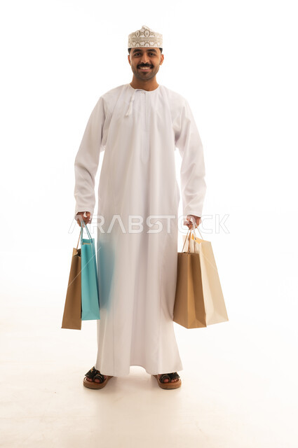رجل عماني يحمل أكياس تسوق على خلفية بيضاء