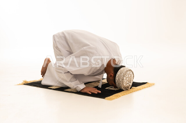 رجل عماني يصلي السجود على خلفية بيضاء