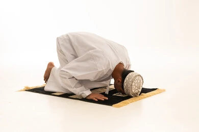 رجل عماني يصلي السجود على خلفية بيضاء