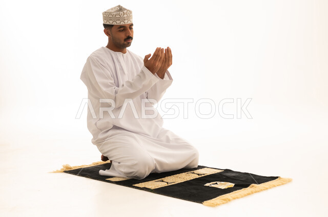 رجل عماني يصلي ويدعو على خلفية بيضاء