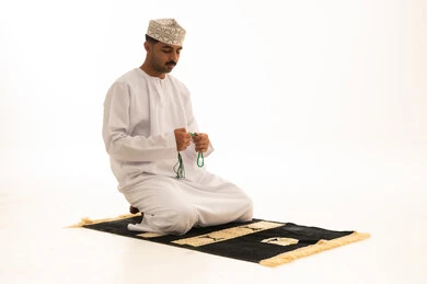 رجل عماني يصلي بالسبحة على خلفية بيضاء