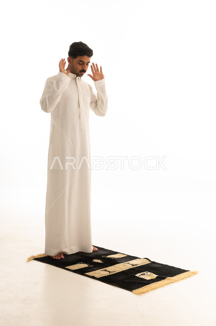 رجل سعودي يؤدي الصلاة على خلفية بيضاء