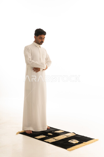 Saudi Man in Traditional Thobe Praying on Mat