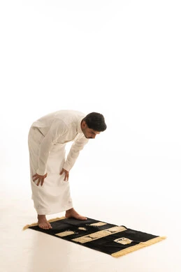 رجل سعودي يؤدي وضعية الركوع على سجادة الصلاة