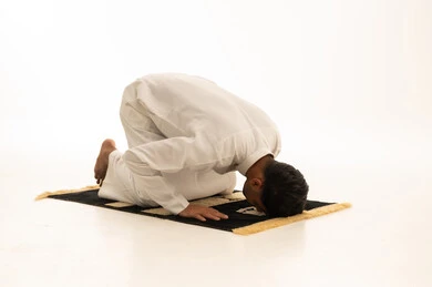 رجل سعودي في وضعية السجود على خلفية بيضاء