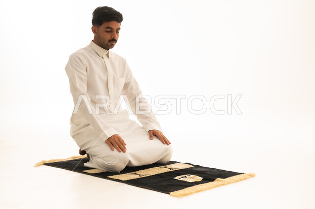 Saudi Man Praying in White Thobe on Rug