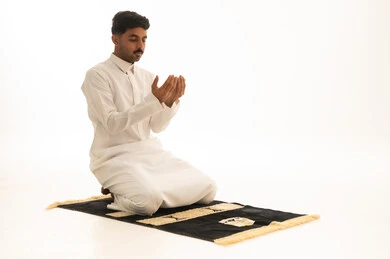 رجل سعودي يدعو ويصلي على سجادة الصلاة