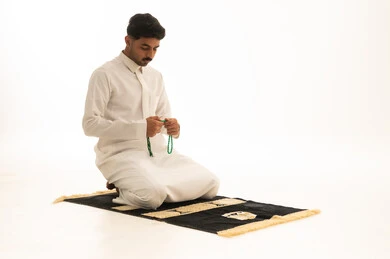 رجل سعودي بالثوب الأبيض يصلي ممسكاً بالسبحة