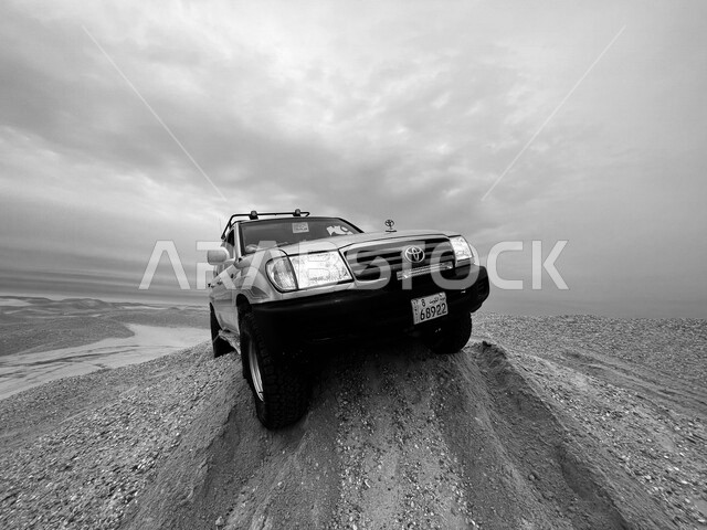 صورة بالأبيض والأسود للكثبان الرملية الصحراوية في المملكة العربية السعودية ، الرمال الناعمة ، جمال المناظر الطبيعية الصحراوية في السعودية ، جيب تويوتا الرياضي بتصميم عصري جذاب تسير في وسط الصحراء ، صحاري السعودية