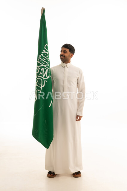 رجل سعودي يحمل العلم الوطني على خلفية بيضاء