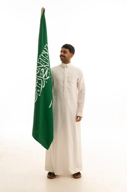 رجل سعودي يحمل العلم الوطني على خلفية بيضاء