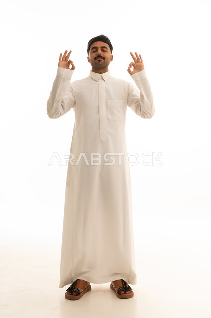 رجل سعودي بالثوب الأبيض يمارس التأمل خلفية بيضاء