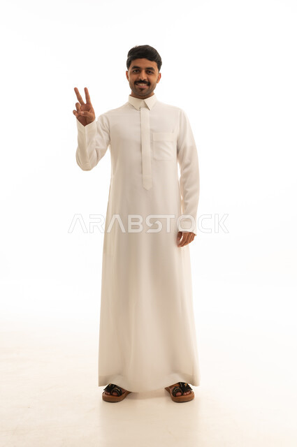 رجل سعودي بالثوب الأبيض يشير بعلامة النصر