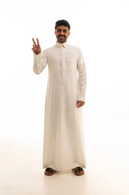 رجل سعودي بالثوب الأبيض يشير بعلامة النصر