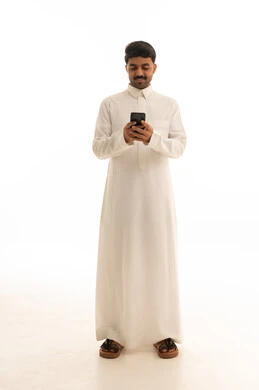 رجل سعودي بالثوب التقليدي يستخدم الهاتف الذكي