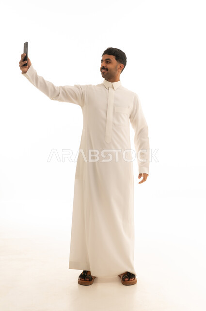 رجل سعودي بالثوب الأبيض يلتقط سيلفي خلفية بيضاء