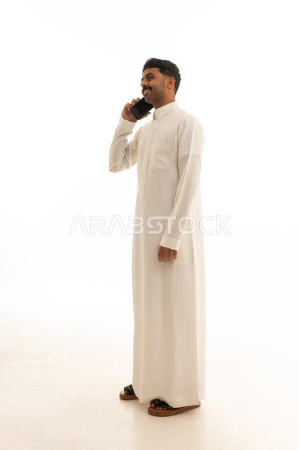 Saudi Man in White Thobe Talking on Smartphone