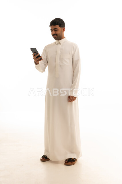 Saudi Man in White Thobe Using Smartphone Full Body