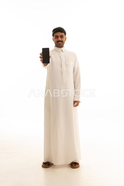 رجل سعودي بالثوب التقليدي يحمل هاتف ذكي