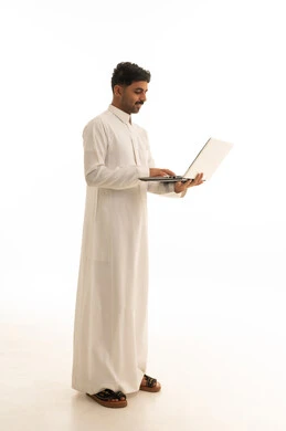رجل سعودي بالثوب يستخدم لابتوب على خلفية بيضاء