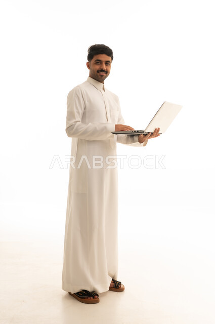 رجل سعودي بالثوب يستخدم لابتوب بخلفية بيضاء