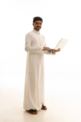 رجل سعودي بالثوب يستخدم لابتوب بخلفية بيضاء