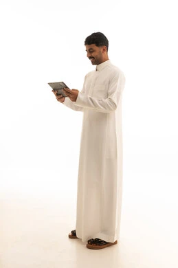 رجل سعودي بالثوب الأبيض يستخدم جهاز لوحي بخلفية بيضاء