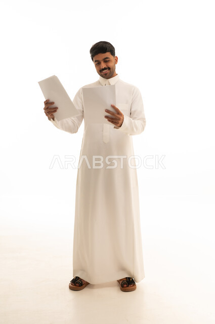 رجل سعودي يراجع مستندات ورقية بخلفية بيضاء