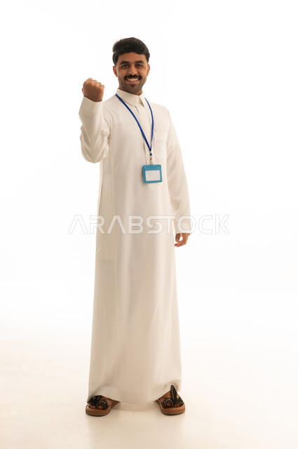 رجل سعودي بالثوب وبطاقة الهوية يشير بالنجاح
