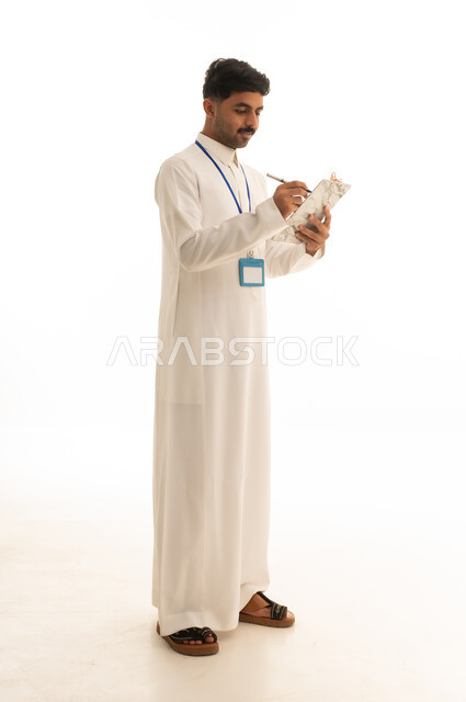 موظف سعودي بالثوب الأبيض يكتب على لوحة ملاحظات