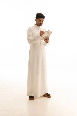 رجل سعودي بالثوب الأبيض يكتب على لوحة ملاحظات