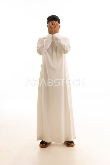 رجل سعودي بالثوب الأبيض يغطي وجهه في الاستوديو