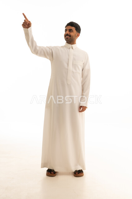 رجل سعودي بالثوب الأبيض يشير للأعلى بخلفية بيضاء