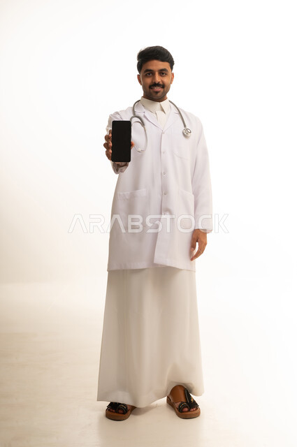 طبيب سعودي يحمل هاتف ذكي على خلفية بيضاء