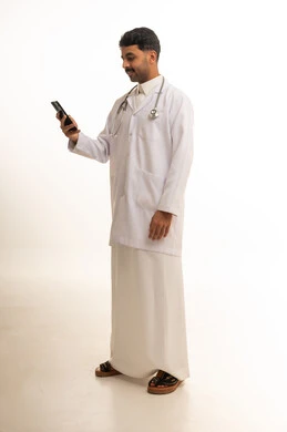 طبيب سعودي يرتدي معطفاً طبياً ويستخدم الجوال