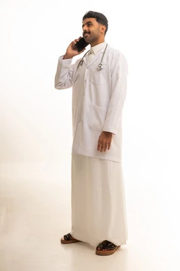 طبيب سعودي بالمعطف الطبي يتحدث بالهاتف الذكي