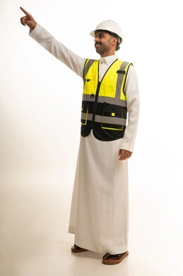 مهندس سعودي بسترة سلامة يشير للأعلى بخلفية بيضاء