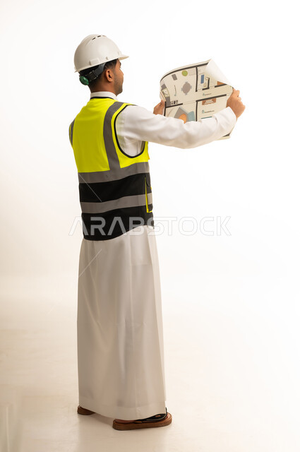 مهندس سعودي يرتدي ملابس السلامة مع مخطط معماري