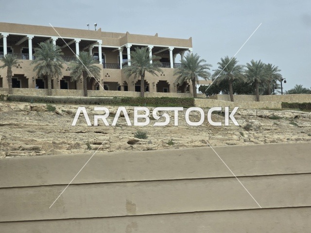 The old walls of Diriyah in the city of Riyadh, Saudi Arabia, are ancient historical archaeological landmarks, showcasing ancient architectural engineering art. A picture of the archaeological buildings and mud houses in the Al-Turaif neighborhood in Diriyah, with green palm trees, represents the heritage tourism areas in Saudi Arabia.