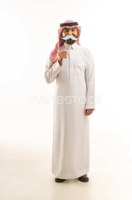 رجل سعودي بالثوب التقليدي يحمل شارب مستعار