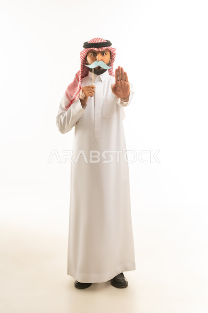 رجل سعودي بالثوب التقليدي مع شارب ورقي وإشارة توقف