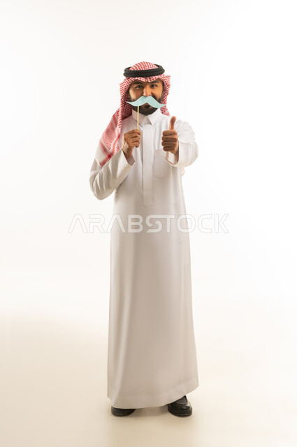 رجل سعودي بالزي التقليدي يحمل شارب ورقي